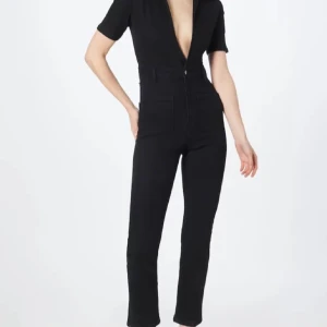 Svart jumpsuit med dragkedja - Säljer en svart jumpsuit med korta ärmar och djup v-ringning. Modellen har raka ben, hög midja och dragkedja framtill. Materialet ser ut att vara stretchigt och bekvämt, perfekt för en clean och stilren look. Obs- ingen dragkedja framtill (upptill). Smal och lite i storleken