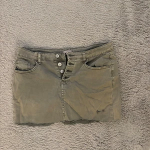Lätt grön lågmidjad jeanskjol - Säljer en grön jeans kjol som har låg midja. Den gröna färgen är lite solfärgad så den är inte så stark längre. Storlek M skulle jag säga 