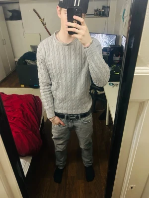 Grå kabelstickad tröja - Säljer en grå kabelstickad tröja från Monte Sport. Tröjan har rund halsringning, ribbade muddar och nederkant samt ett klassiskt kabelmönster. Perfekt för dig som gillar stilren och enkel design.