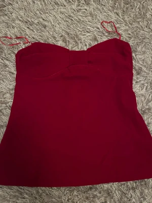 Röd linnetopp med rosettdetalj Bik Bok - Snygg röd linnetopp från Bik Bok utan axelband och en söt rosettdetalj framtill. Toppen har en lätt utsvängd passform och dragkedja i ryggen för enkel påklädning. Perfekt för dig som vill ha en enkel men ändå chic look. (Helt ny med prislapp) nypris: 400kr.                                                            Säljs för: 350kr