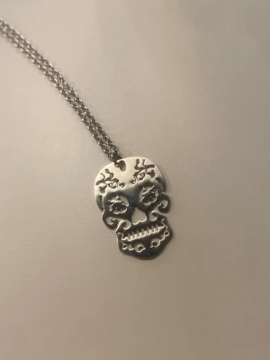 Skelett halsband  - Bilderna visar ett halsband med dödskalleberlock i silverfärgad metall, ej äkta silver. Helt oanvänd! 🫶 berlocken ser likadan ut på båda sidor och är tunn.