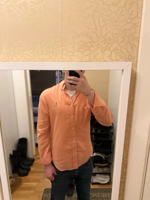 Rosa skjorta från Ralph Lauren S - Säljer en snygg rosa skjorta från Ralph Lauren i slim fit. Skjortan är i 100% bomull, har klassisk krage, knappar framtill och den ikoniska broderade loggan på bröstet. Perfekt till jeans eller chinos för en clean och fräsch look.