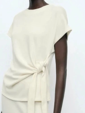 Zara topp med knytning  - Super snygg vit topp från zara som inte säljs längre🤗 Säljer då den inte kommer till användning💓💓 Storlek M men sitter som en S då man kan knyta bandet hur man vill 🤗🤗🥰🥰