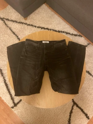 Svarta jeans från Smog - Tjena👋 Säljer ett par svarta jeans från Smog i storlek 28/30🙌 Jeansen har klassisk femficksdesign, raka ben och subtila slitningar framtill för en snygg, avslappnad look🤩 Tillverkade i mjukt jeansmaterial som sitter skönt hela dagen🙏 Vid frågor: Meddela oss📩