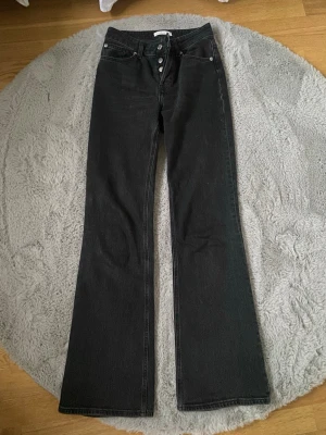 Svarta bootcut jeans med hög midja - Snygga svarta jeans ifrån hm med bootcut passform och hög midja. Klassisk femficksmodell med knappgylf och raka bakfickor