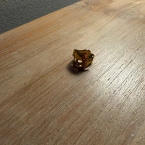 Guldfärgad ring från Pilgrim - Säljer en chunky guldfärgad ring från Pilgrim med vågig, häftig form. Ringen har en blank yta och är perfekt för dig som vill ha något unikt i smyckeslådan. Den är helt oanvänd