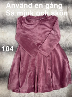 Rosa sammetsklänning med lång ärm - Supersöt rosa sammetsklänning med lång ärm och rundad hals med liten volangkant. Mjuk och skön känsla, perfekt för dig som gillar bekväma och fina plagg. Passar till många olika tillfällen.🌸 Använd en gång. Så mjuk och skön. Storlek 104 