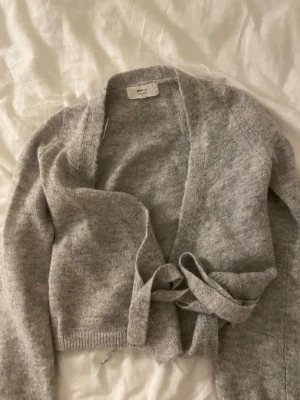 Grå omlottkofta från Gina Tricot - stickad grå tröja som man kan knyta ifrån Gina trixig i väldigt bra skick 