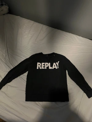 Svart sweatshirt från Replay - Säljer en svart sweatshirt från Replay med stor vit logga framtill. Tröjan har rund halsringning, långa ärmar och mjukt material på insidan. Perfekt för dig som gillar enkel och stilren streetwear.