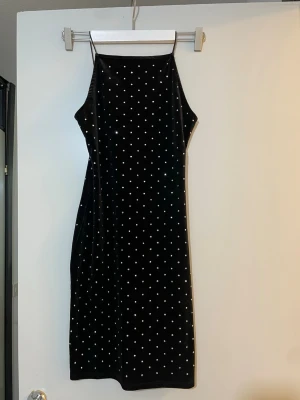 Svart sammetsklänning med diamant 💎 prickar  - Supersnygg svart sammetsklänning med tunna axelband och vita prickar över hela klänningen. Klänningen är perfekt för dig som vill sticka ut lite extra. Materialet är mjukt och ger en lyxig känsla.