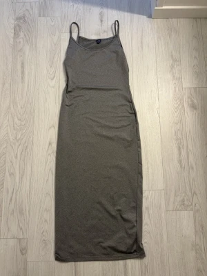 Grå långklänning från SHEIN - En enkel och stilren grå långklänning från SHEIN i storlek S. Klänningen har smala axelband och rak passform som ger en clean look. Tillverkad i mjukt och stretchigt material som känns bekvämt mot huden. Perfekt att styla med sneakers eller sandaler.