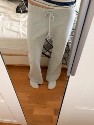 Grå mjukisbyxor från Brandy Melville - Säljer ett par ljusgrå mjukisbyxor från Brandy Melville i 100% bomull. Byxorna har normal passform, dragsko i midjan och raka ben med lite utsvängd siluett💞säljer eftersom att de vart lite för stora, jag brukar ha xs i mina byxor men jag hade sagt att dessa är i M storlek💞💞 innerbenslängd:79 cm       Waist:85cm