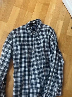 Rutig Peak Performance skjorta XL - Säljer en klassisk rutig skjorta från Peak Performance i svart och vitt. Skjortan har lång ärm, knappar framtill och en mjuk bomullskänsla. Perfekt till jeans eller chinos för en avslappnad look.