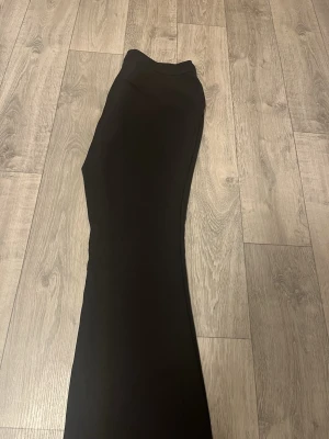 Svarta bootcut kostymbyxor Gina Tricot - Säljer ett par svarta kostymbyxor från Gina Tricot i storlek 42. Byxorna har bootcut-modell med hög midja och klassiska fickor bak. Snyggt och stilrent snitt som passar till många olika looks. Materialet känns mjukt och följsamt.