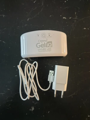 Depend GeliQ UV/LED lampa - Professionell UV/LED-lampa med salongkvalitet utvecklad för Depend Gel iQ Gel Polish och Depend Gel iQ Gel Nail Strips.  Liten och smidig med inbyggd timer med korrekta tidsintervaller: **Gel iQ Gel Polish:** 30 sekunder i lampan/på applicering av baslack, färg och topplack för en säker och optimal härdning. Utförlig bruksanvisning finns i förpackningen. **Gel iQ Gel Nail Strips:** 60 sekunder i lampan.   Bara öppnad, ej använd. Nyskick!
