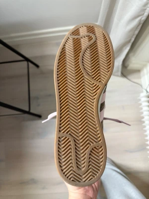 Adidas Campus sneakers brun/rosa mocka - Säljer ett par Adidas Campus sneakers i brun mocka med ljusrosa detaljer och snörning. Skorna har klassiska tre ränder på sidan, Adidas-logga på häl och plös samt en beige sula. Insidan är fodrad i rosa tyg och yttersulan är i gummi.