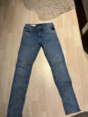 Replay Hyperflex ljusblå jeans - Säljer ett par Replay Hyperflex jeans i ljusblå tvätt. Klassisk femficksmodell med raka ben. Jeansen har normal passform och är tillverkade i stretchigt jeansmaterial för extra komfort. Märkespatch bak i midjan.