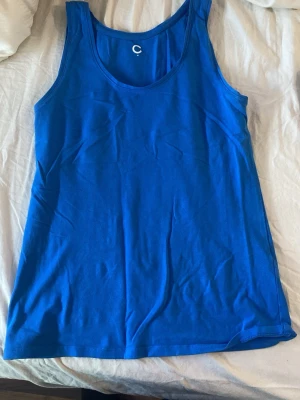 Kornblå linnetopp från C - En enkel och stilren kornblå linnetopp från C. Toppen är ärmlös med rundad halsringning och tillverkad i mjuk bomull som känns skön mot huden 