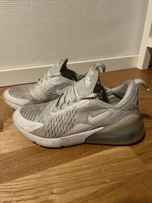 Nike Air Max 270 vita sneakers - Nike Air Max 270 sneakers i helvitt med mesh-överdel och stora synliga Air-enheter i hälen. Skorna har snörning, rund tå och en chunky sula som ger grym komfort. Perfekta för dig som gillar sportig och clean stil. Lite smutsiga men om man rengör de blir dom nog som nya☺️