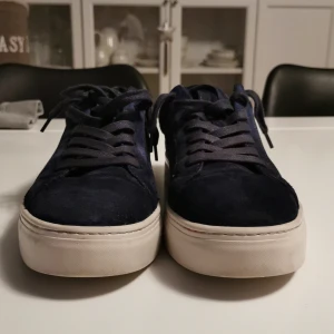 Mörkblå sneakers från Vagabond - Snygga marinblåa sneakers från Vagabond i mocka med vita, tjocka sulor och klassisk snörning. Skorna har en rund tå och stilren design som passar perfekt till jeans eller chinos. Insidan är fodrad med textil och läder för extra komfort. Använda 2 gånger, ny pris 1400kr