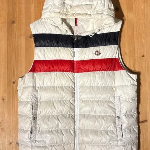 Moncler Timothe Gilet - Moncler Timothe Vest, Selling this incredibly nice Moncler Timothe Vest in the color White🤍. Size Moncler size 5 which corresponds to an X-Large. The vest has an incredible number of cool details and has a new price of over 900usd, As pictured nicely used, no huge signs of wear. 700++ sales references so you are shopping in safe hands here. See a lot of fakes going around of Moncler in the past, ensure safe trading with a good and safe price and seller, proof that it is genuine can be provided i