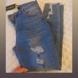 Blå ripped jeans från SHEIN SXY - Snygga blå jeans från SHEIN SXY med flera slitningar och ripped detaljer längs benen. Modellen är slim och har klassisk femficksdesign. Jeansen är tillverkade i stretchig denim för en bekväm passform och har normal midja.