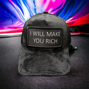 Svart keps med text I WILL MAKE YOU RICH - Svart keps med mjuk, pälsliknande yta och mesh på sidorna. Framtill sitter en stor patch med vit text: 'I WILL MAKE YOU RICH'. Justerbar baktill för perfekt passform. Perfekt statement-piece för dig som vill sticka ut.