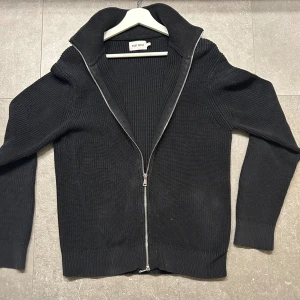  Full zip kofta  - En as snygg full zip ifrån East West i färgen svart. Tröjan är näst intill oanvänd och passar perfekt nu till hösten.
