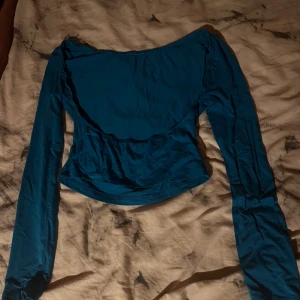 Blå croppad topp med öppen rygg SHEIN - Säljer en blå långärmad croppad topp från SHEIN i storlek S. Toppen har en snygg öppen rygg och figurnära passform. Perfekt att styla med jeans eller kjol för en trendig look.