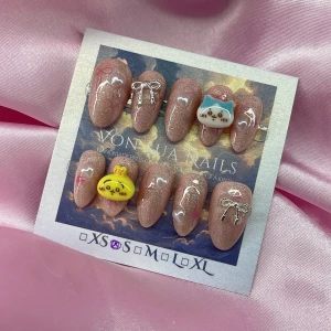 ChikawaSet (S);Short Almond;Curved - Handgjorda press on-naglar i en kort mandelform med skimrande rosa bas, dekorerade med små hjärtan, silverrosetter och söta 3D-figurer i form av en blå katt och en gul kanin. Perfekt för dig som vill ha unika och gulliga naglar med extra detaljer.S: 15 mm, 11,5 mm, 12 mm, 11 mm, 9 mm 