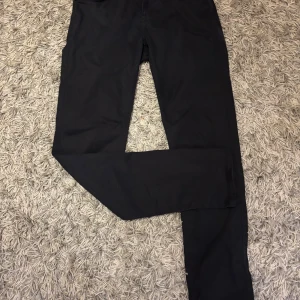 Svarta stretchiga byxor från Sand - Svarta byxor från Sand med superstretch för extra komfort och modern passform. Klassisk femficksmodell med raka ben och diskreta sömmar. Perfekta för dig som vill ha stilrena och bekväma byxor med snygg passform. Inte alls använda.