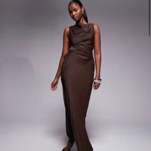 Brun långklänning med öppen rygg - Säljer en elegant brun långklänning med snygg drapering och öppen rygg. Klänningen är helt ny och oanvänd.