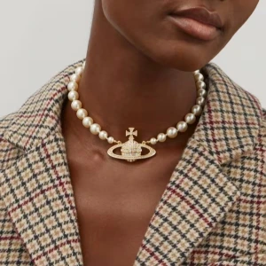 Vivienne Westwood pärlhalsband - Ikoniskt halsband från Vivienne Westwood med stora vita pärlor och ett gnistrande guldfärgat orb-hänge dekorerat med stenar. Perfekt statement-piece för att lyfta vilken outfit som helst.