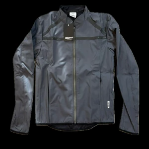 Fristads Softshelljacka 4557 LSH - Fristads Softshelljacka 4557 LSH är en modern och funktionell jacka som kombinerar stil, komfort och slitstyrka. Tillverkad i ett vind- och vattenavvisande softshellmaterial som samtidigt andas, vilket gör den perfekt för både arbete och fritid i varierande väderförhållanden.  Egenskaper: 	•	Vind- och vattenavvisande material med god andningsförmåga 	•	Figursydd passform för maximal rörelsefrihet 	•	Hel dragkedja fram med skyddad insida mot vind 	•	Två sidfickor med dragkedja