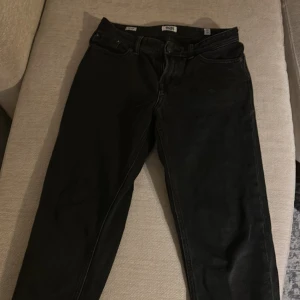 Svarta jeans från Jack & Jones - Svarta jeans från Jack & Jones med klassisk femficksdesign och raka ben. Jeansen har en stilren look med svarta sömmar och bälteshällor. Perfekta till en avslappnad streetstil eller när du vill hålla det enkelt.