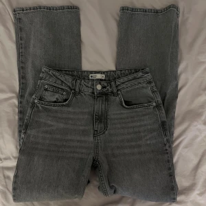Gråa jeans - Gråa jeans från Gina Tricot med rak passform. Snygg tvättad grå färg som passar till allt. Har en en fläck på nedre delen av framsida ben. Jeansen har hög midja. 