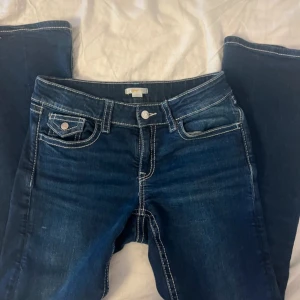 Blå bootcut jeans från Gina Tricot - Snygga mörkblå jeans från Gina Tricot i bootcut-modell med kontrastsydda sömmar och klassiska fickor både fram och bak. Jeansen har normal passform och är tillverkade i jeansmaterial med en cool tvättad look.