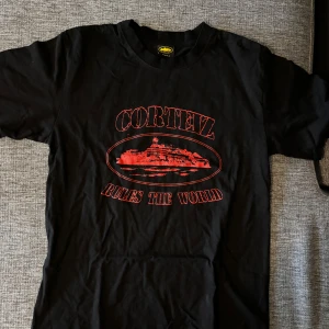 Svart Cortez t-shirt med röd print - Svart t-shirt från Cortez i storlek small med röd grafisk print och texten 'Cortez Rules The World' på framsidan. Klassisk rund hals och korta ärmar. Materialet känns som mjuk bomull, perfekt för en chill streetwear-look.