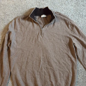 Beige half zip tröja John Henric - Snygg beige tröja från John Henric med half zip och ribbad krage i mörkare ton. Tröjan är långärmad och har en stilren, klassisk look som passar perfekt till jeans eller chinos. 