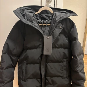 Svart macmillan parka  från Canada Goose  - Säljer du denna svarta macmillan parka jacka från Canada goose den är helt ny med prislapp köpt här på Plick. Den är i storlek M men passar även S. Hör gärna av er för fler frågor!