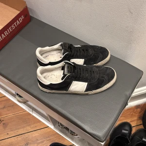 Valentino Garavani svartvita sneakers - Svartvita sneakers från Valentino Garavani med snygg kontrast mellan svart mocka och vita skinnpaneler. Klassisk rund tå, platt sula och svarta snören. Märkeslogga på plösen och insidan. Perfekta för dig som gillar stilrena och lyxiga sneakers. Allt og medföljer. OBS! pris ej hugget i sten
