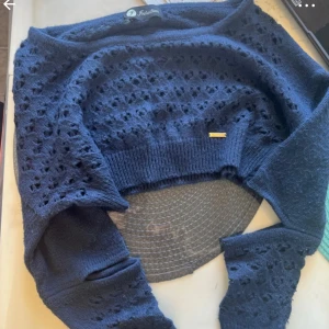 Mörkblå stickad tröja från Intuition - Snygg mörkblå stickad tröja från Intuition med hålmönster och ribbade muddar. Tröjan har lång ärm och en croppad passform som ger en trendig look. Perfekt för dig som gillar detaljer och vill ha något unikt i garderoben. Snabb leverans 📦 snyggast priser ✨