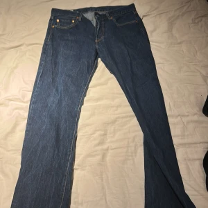 Levi's 501 blå jeans straight fit - Klassiska blå Levi's 501 jeans med raka ben och femficksmodell. Jeansen har gylf med knappar och är tillverkade i slitstarkt denim. Perfekta för dig som gillar en tidlös och enkel stil.