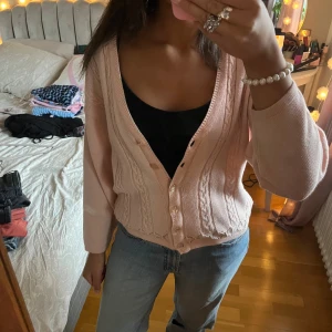 Ljusrosa stickad kofta - Supersöt ljusrosa stickad kofta med v-ringning och fina pärlemorknappar framtill. Köpt second hand o vet inte original märket! 