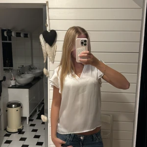 Vit sidenblus med volangärm - Säljer en superfin vit blus i glansigt sidenmaterial. Blusen har korta volangärmar och en snygg v-ringning. Perfekt att styla med jeans eller kjol för en fräsch look. Enkel och fin att styla❣️❣️