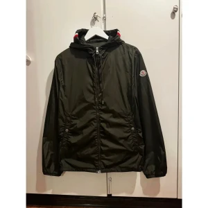  vindjacka från Moncler med huva -  vindjacka från Moncler med huva och dragkedja framtill. Jackan har Moncler-logga på ärmen, två fickor med tryckknappar och snygga rödvita detaljer på huvan. Storlek M😊