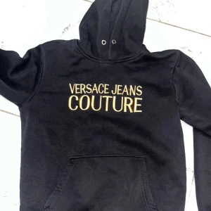 Svart hoodie  - Svart hoodie. Klassisk huva med snörning och stor magficka framtill. Perfekt för dig som vill sticka ut med en lyxig streetstyle-look.