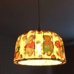 Retro Barnlampa med djurmotiv - Diameter 35cm Höjd 20cm. Charmig barnlampa med tygskärm dekorerad med söta nallebjörnar, kaniner och leksaker. Skärmen är i gott skick utan synliga fläckar eller skador. Perfekt till barnrummet för en mysig och lekfull atmosfär. Lågenergilamba ingår. Kolla mina andra annonser för samfrakt. 