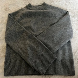 Grå stickad tröja från H&M XS - Mysig grå stickad tröja från H&M i storlek XS. Tröjan har en klassisk rund halsringning, ribbade muddar och nederkant samt långärmad passform. Perfekt för lager-på-lager under kyliga dagar. Helt ny aldrig använd!