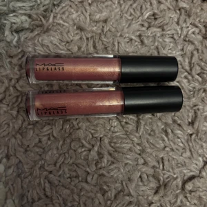 MAC Lipglass i nyansen Nymphette - Två stycken MAC Lipglass i färgen Nymphette, en skimrande rosa med guldton. Ger glansiga, fylliga läppar med en hint av skimmer. Köpt föf 289kr STYCK, säljer 90 kr st, eller 170kr för 2st, en av de är bara testad 1 gången men annars är de båda i helt nyskick.